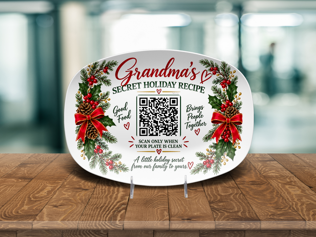 A white oval ceramic serving platter with a festive Christmas design, displayed on a wooden table. The platter features green holly wreaths with red bows, red berries, and the text 'Grandma's Secret Holiday Recipe' along with a scanable QR code.